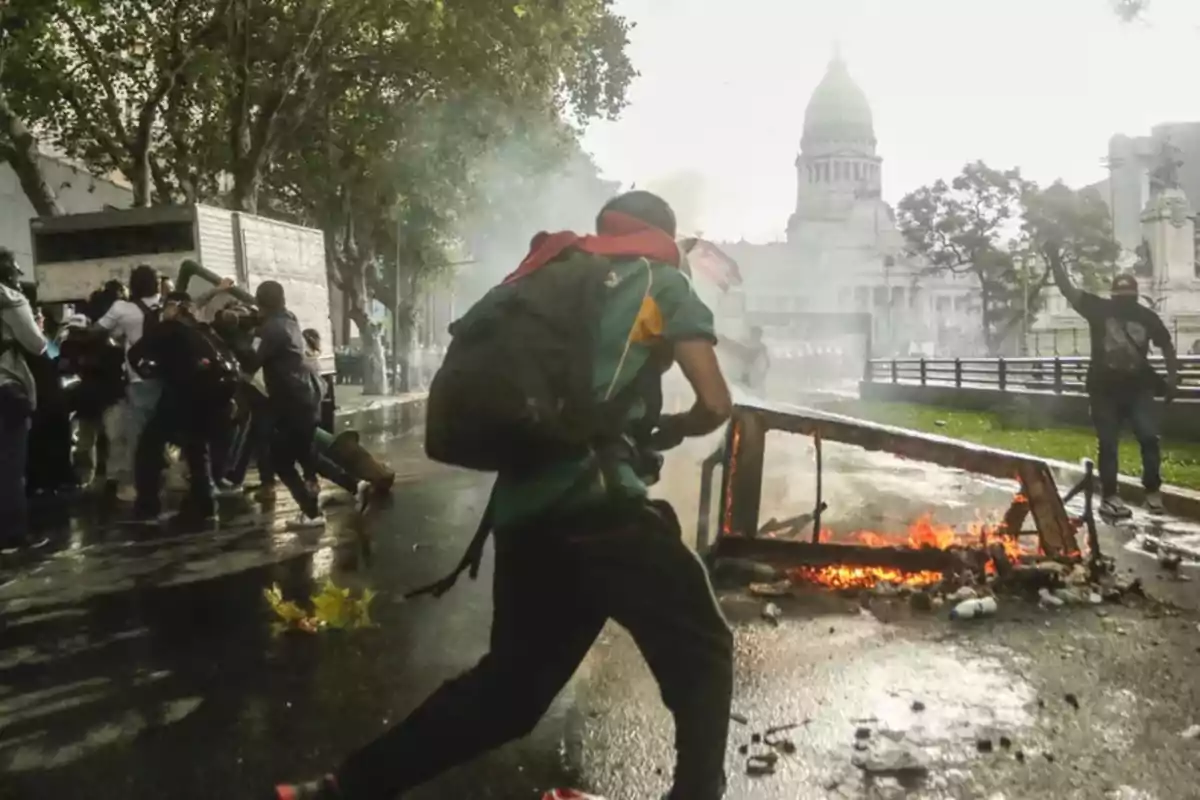 People running and clashing near a burning barricade in front of a government building People running and clashing near a burning barricade in front of a government building