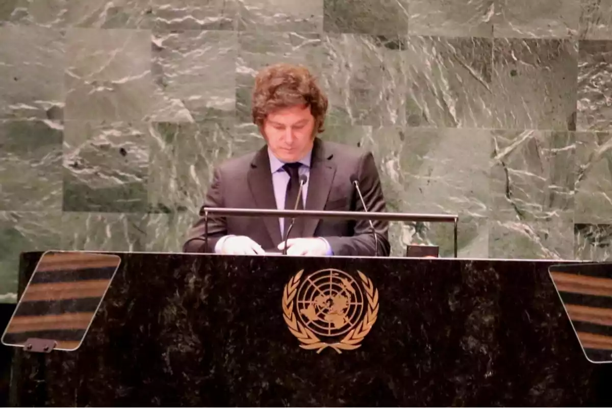 Man in a dark suit speaking at the UN podium with a green marble background Man in a dark suit speaking at the UN podium with a green marble background