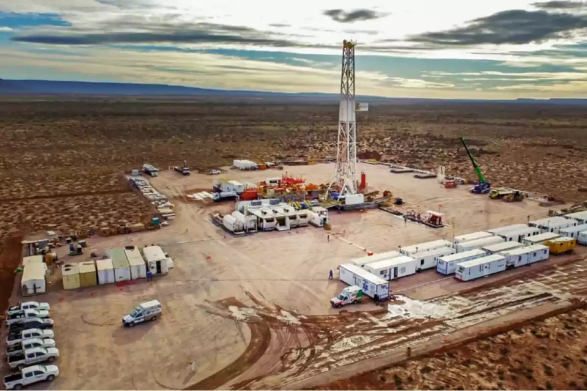 Oil drilling platform in the middle of the desert surrounded by vehicles and temporary modules under a partly cloudy sky Oil drilling platform in the middle of the desert surrounded by vehicles and temporary modules under a partly cloudy sky