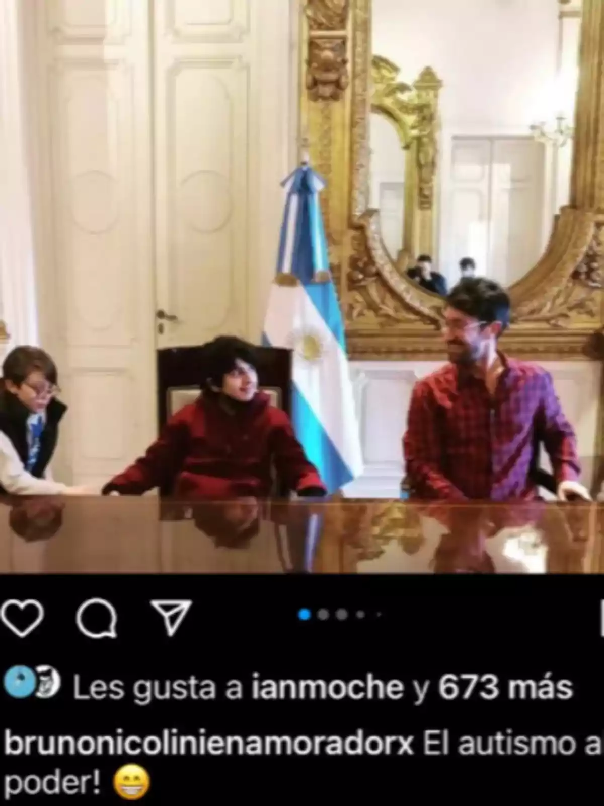 Three people sitting at a table in an elegant room with a large golden mirror and an Argentine flag in the background Three people sitting at a table in an elegant room with a large golden mirror and an Argentine flag in the background