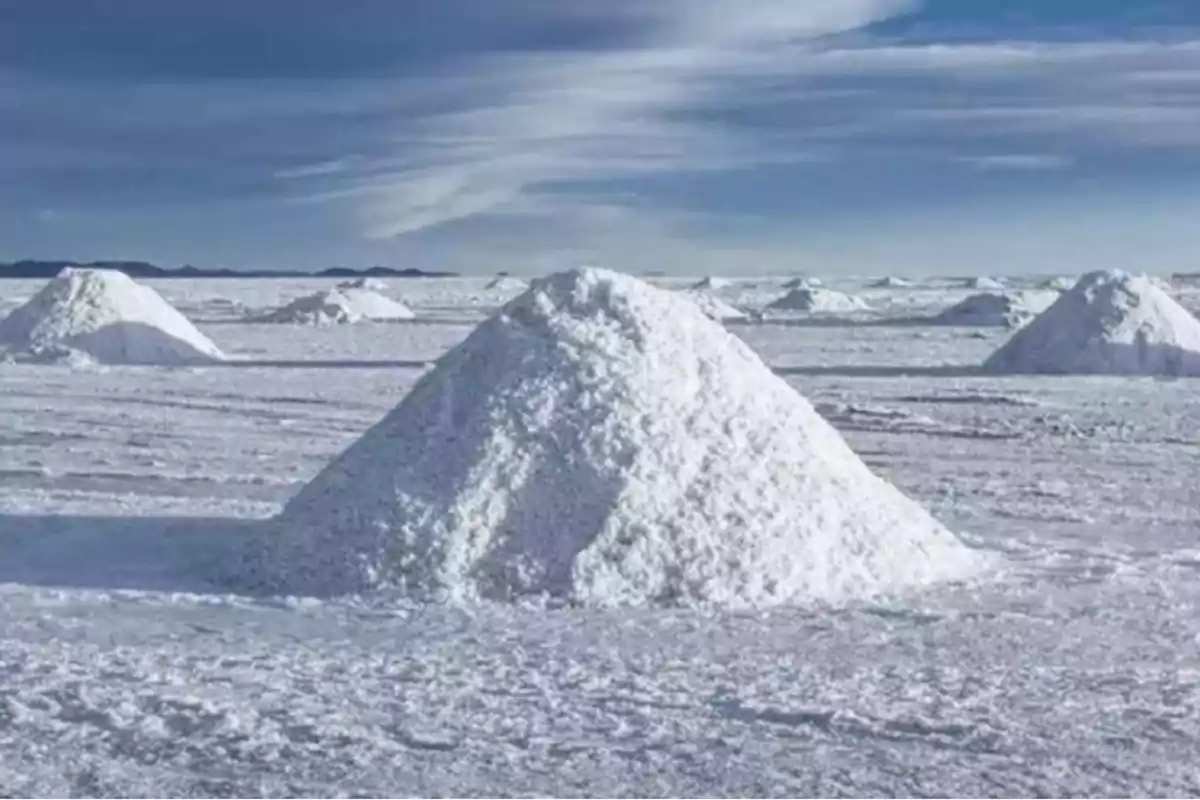 Mounds of salt on a white surface under a partly cloudy sky Mounds of salt on a white surface under a partly cloudy sky