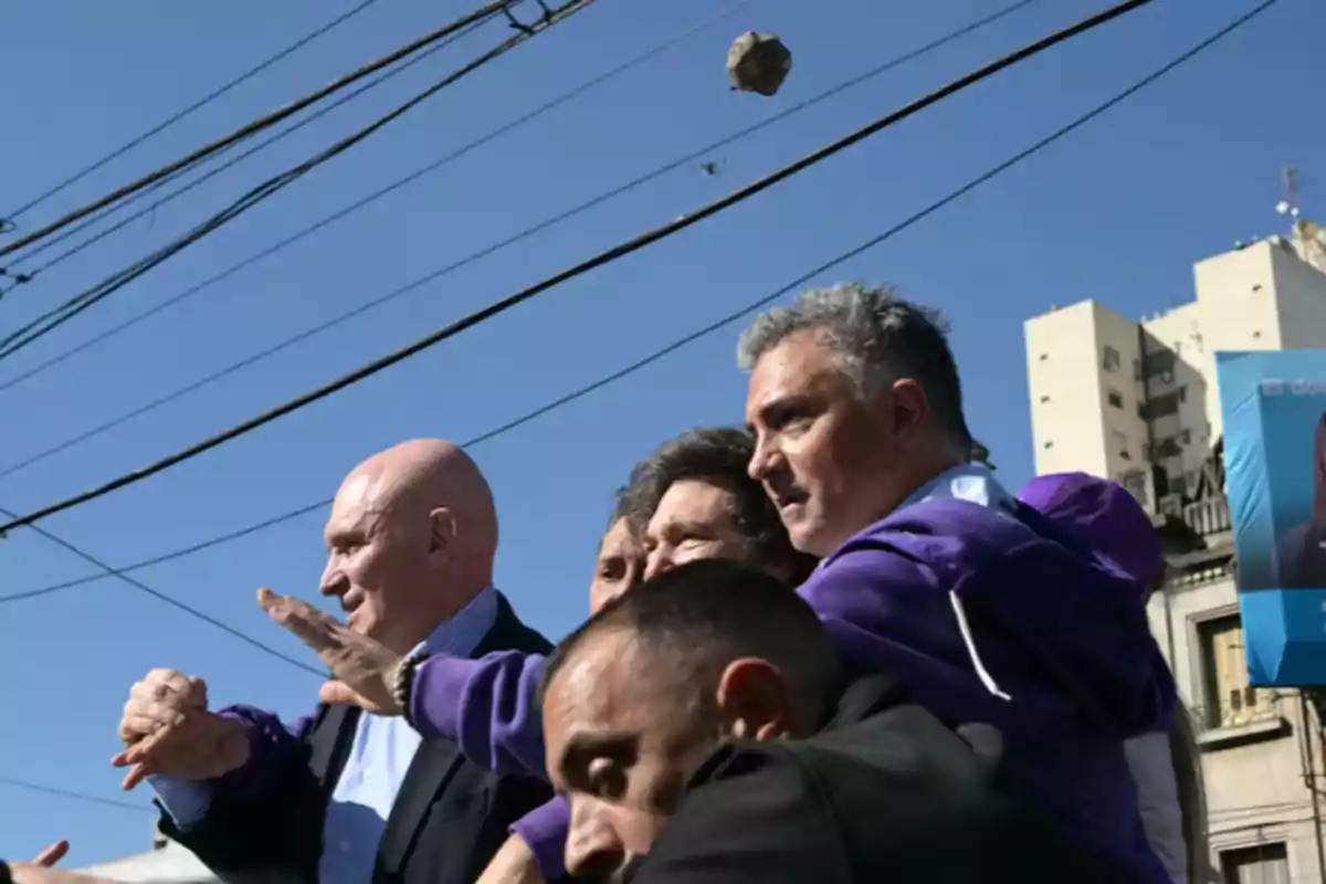 Un grupo de personas en la calle durante un evento público mientras una piedra vuela por el aire sobre ellos Un grupo de personas en la calle durante un evento público mientras una piedra vuela por el aire sobre ellos