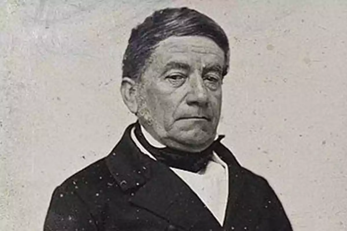 Old black-and-white portrait of an elderly man with a serious expression and short hair combed to one side, dressed in a dark jacket and light-colored jersey