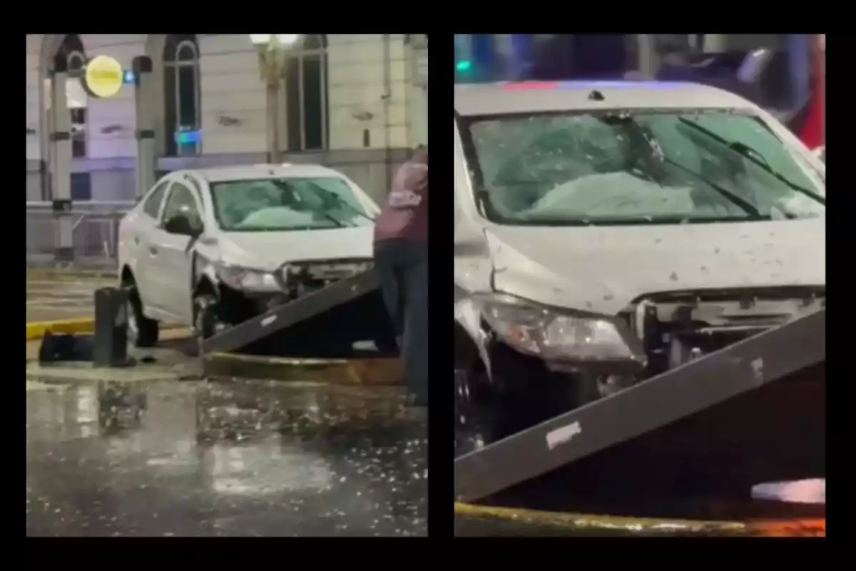 Auto blanco con el parabrisas roto y daños en la parte frontal tras chocar contra una estructura metálica en una calle mojada Auto blanco con el parabrisas roto y daños en la parte frontal tras chocar contra una estructura metálica en una calle mojada