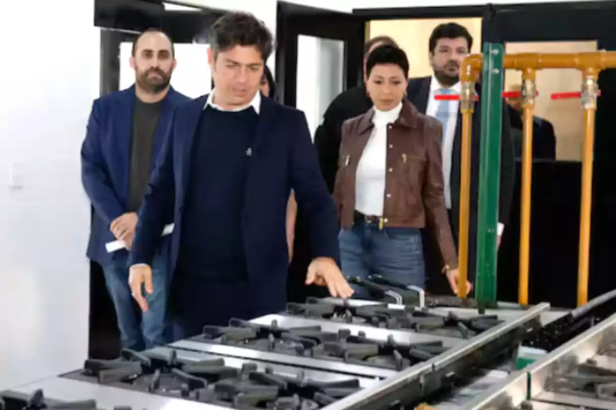 A group of people tours a factory, observing industrial kitchens on a production line. A group of people tours a factory, observing industrial kitchens on a production line.