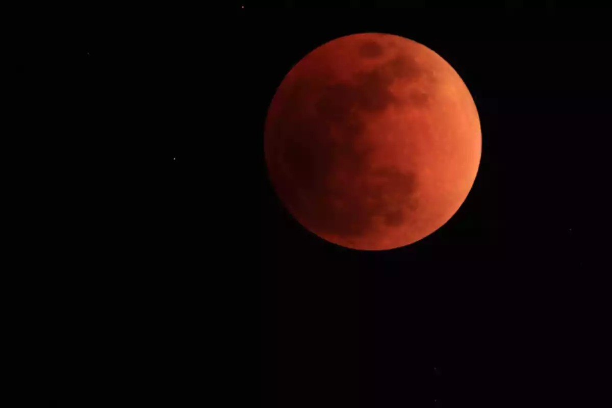 La luna se observa de color rojo durante un eclipse lunar en un cielo oscuro