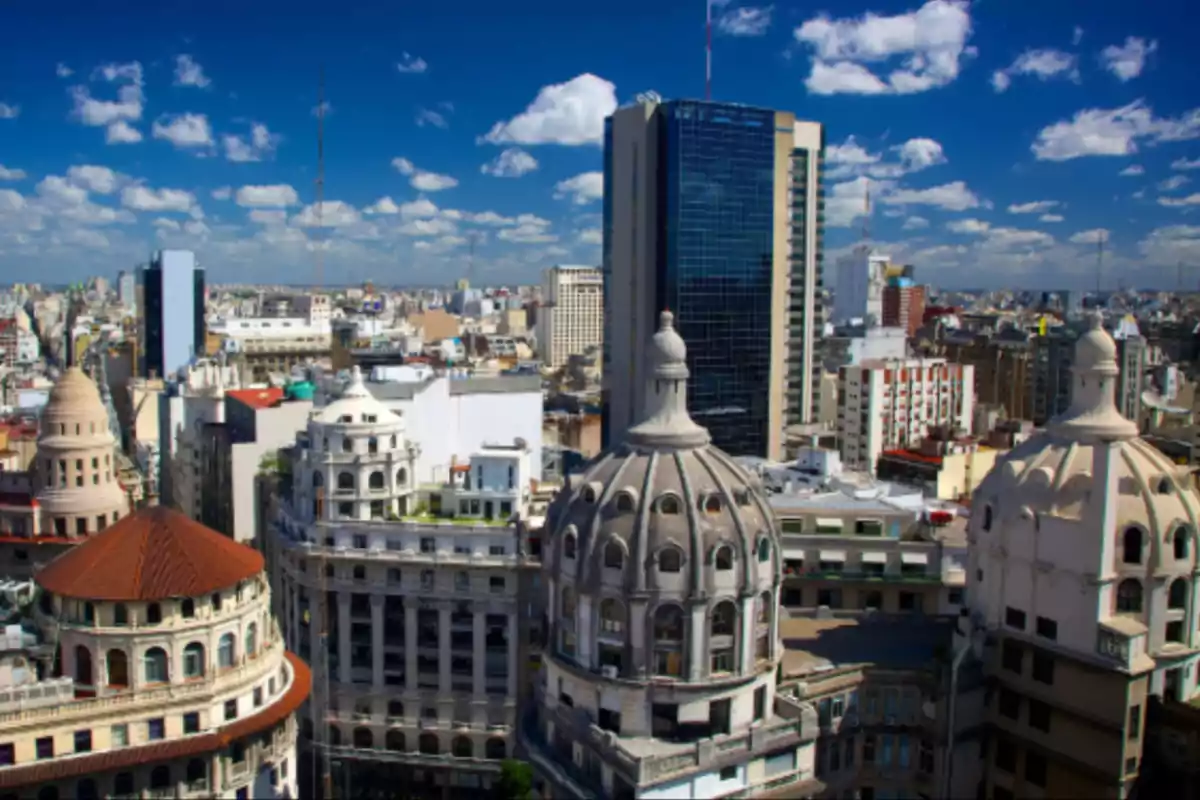 Panoramic view of historic and modern buildings in a city under a blue sky with scattered clouds
