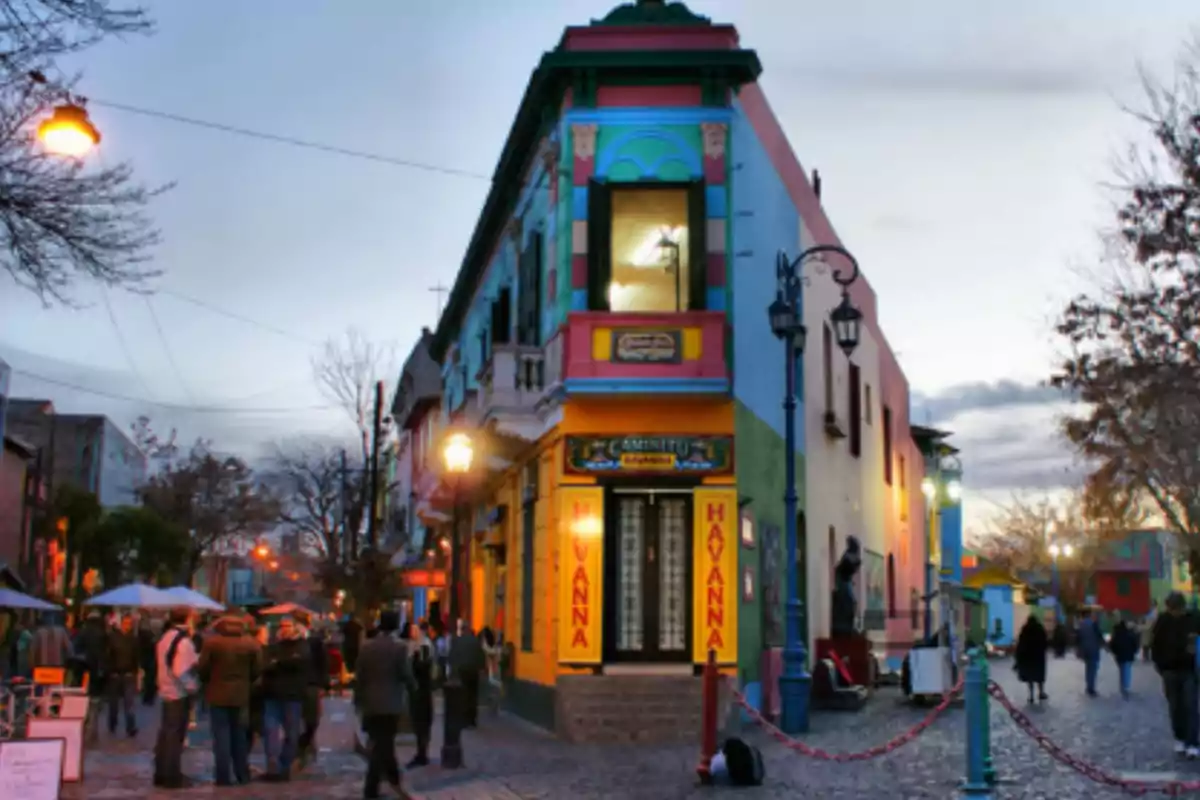Colorful building on a corner of Caminito in Buenos Aires with people walking and streetlights lit at sunset Colorful building on a corner of Caminito in Buenos Aires with people walking and streetlights lit at sunset