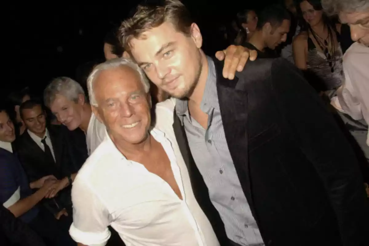 Dos hombres posan juntos y sonríen en una fiesta elegante rodeados de otras personas Dos hombres posan juntos y sonríen en una fiesta elegante rodeados de otras personas