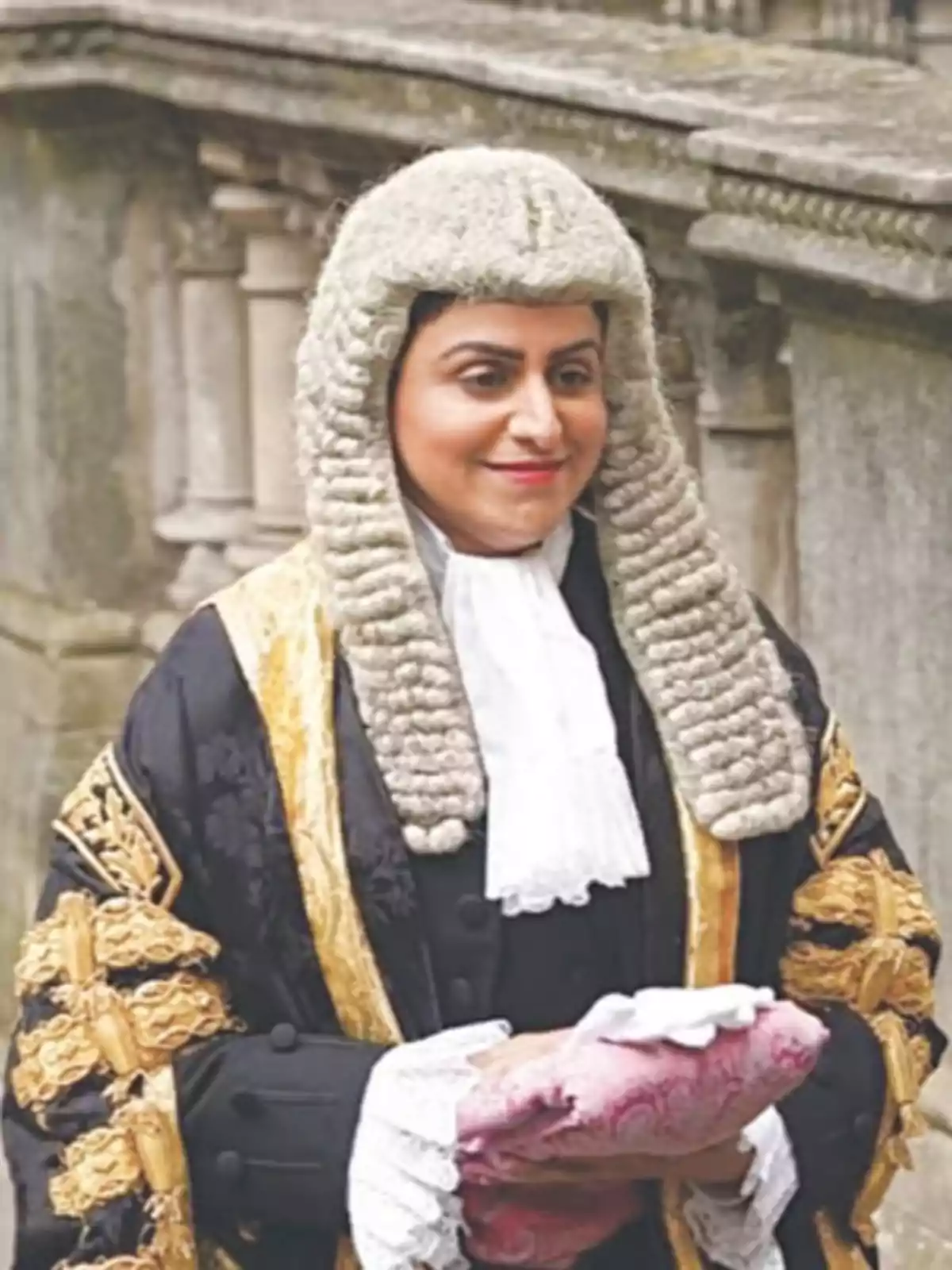 Woman with a traditional wig and ceremonial judge's robe holding a pink cushion in an ancient architectural setting Woman with a traditional wig and ceremonial judge's robe holding a pink cushion in an ancient architectural setting