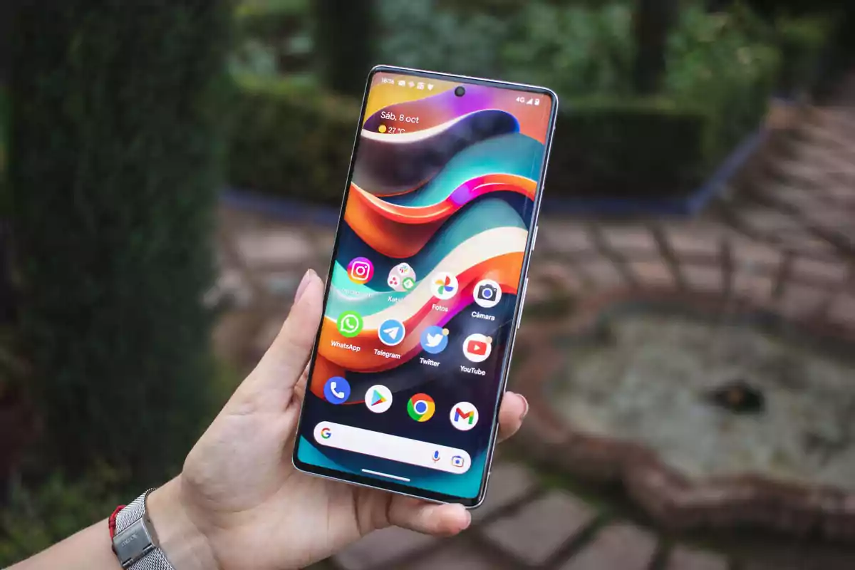 Persona sosteniendo un teléfono inteligente con la pantalla encendida mostrando varias aplicaciones en un entorno al aire libre Persona sosteniendo un teléfono inteligente con la pantalla encendida mostrando varias aplicaciones en un entorno al aire libre