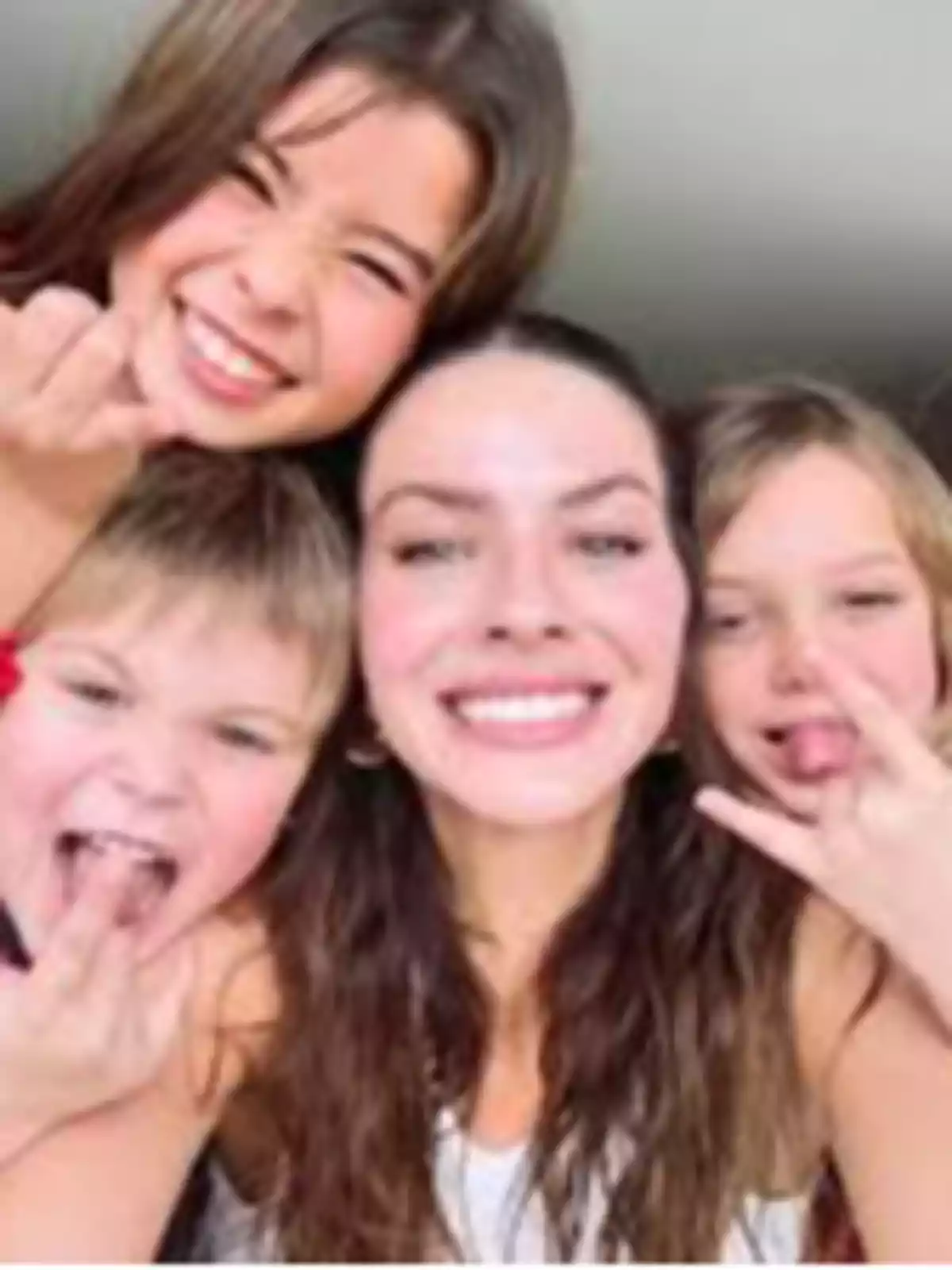 Group of four people smiling and making funny hand gestures while posing for a selfie Group of four people smiling and making funny hand gestures while posing for a selfie