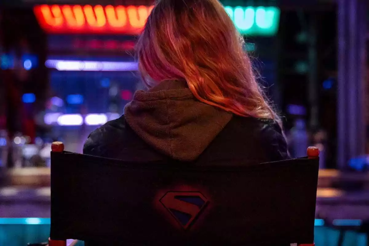 Person sitting with their back to the camera in a chair with the Superman logo in a brightly lit, colorful environment Person sitting with their back to the camera in a chair with the Superman logo in a brightly lit, colorful environment