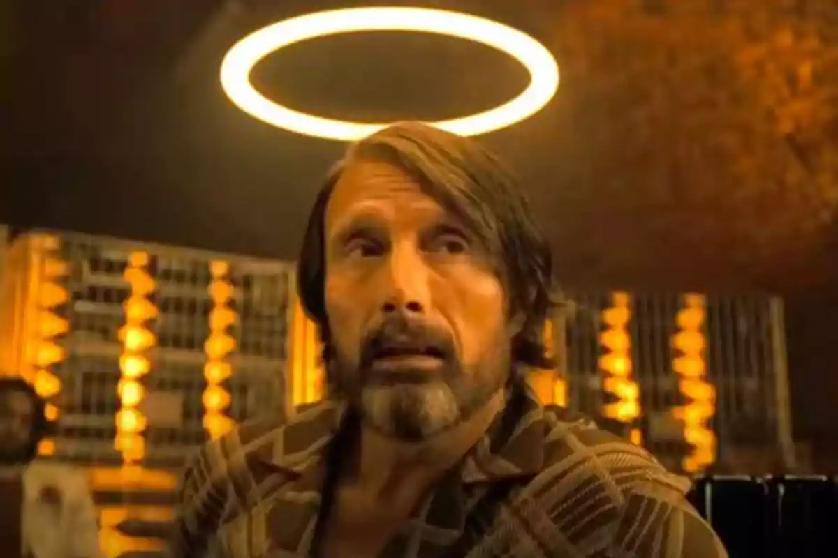 A man with a beard and long hair appears to have a glowing halo over his head due to a circular light in the background. A man with a beard and long hair appears to have a glowing halo over his head due to a circular light in the background.