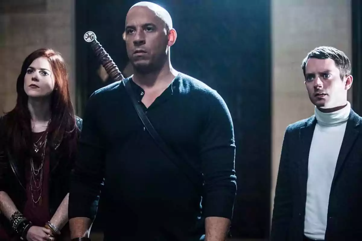 Three people are watching something with serious expressions in a dimly lit room, one of them carrying a sword on their back. Three people are watching something with serious expressions in a dimly lit room, one of them carrying a sword on their back.