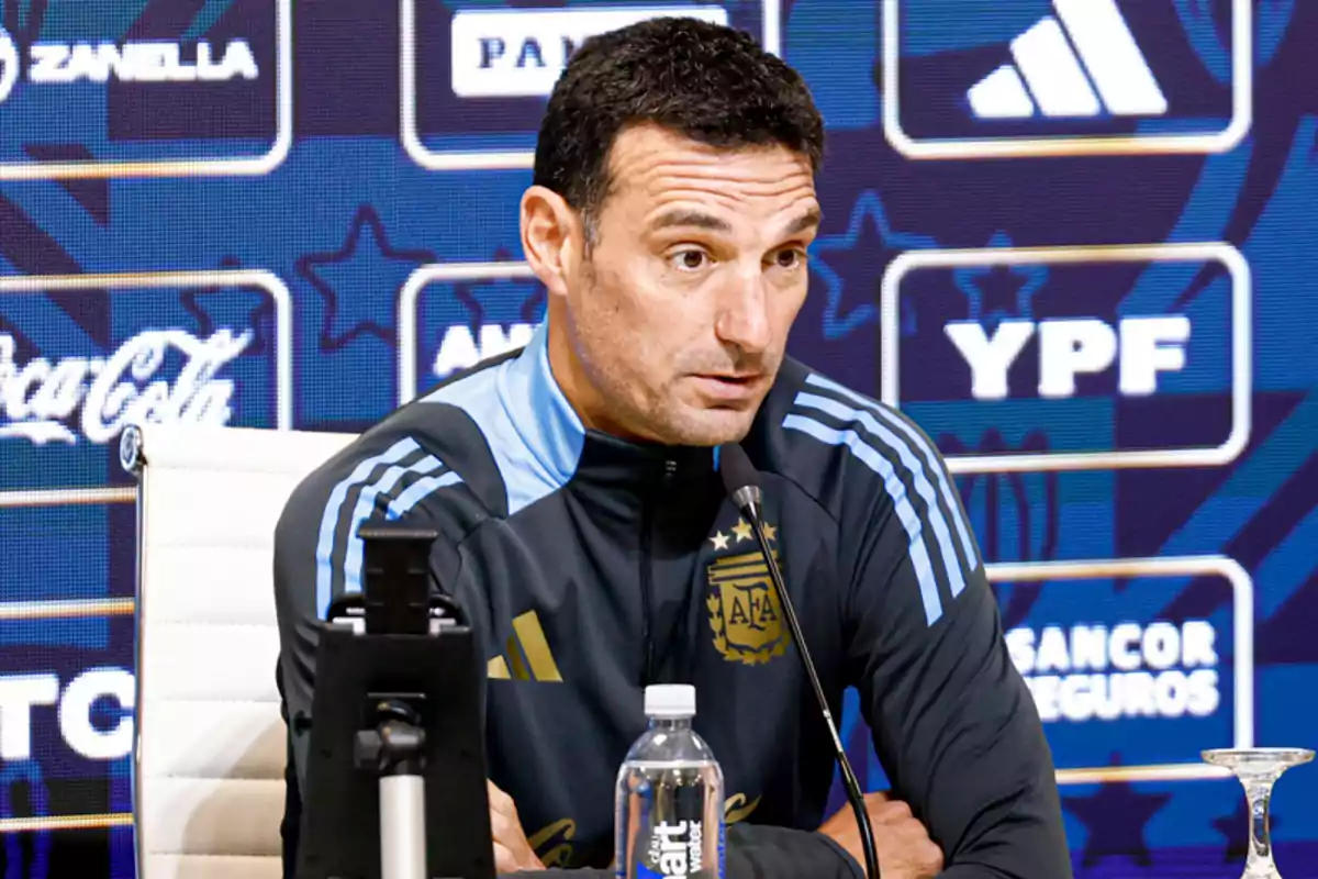 Entrenador de la selección argentina de fútbol hablando en una conferencia de prensa con fondo de patrocinadores y micrófono frente a él Entrenador de la selección argentina de fútbol hablando en una conferencia de prensa con fondo de patrocinadores y micrófono frente a él