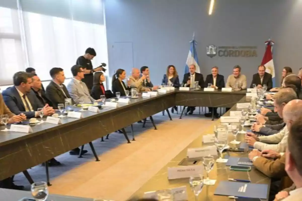 Reunión de varias personas sentadas alrededor de una mesa en una sala de conferencias con banderas y el logo del gobierno de Córdoba en la pared Reunión de varias personas sentadas alrededor de una mesa en una sala de conferencias con banderas y el logo del gobierno de Córdoba en la pared