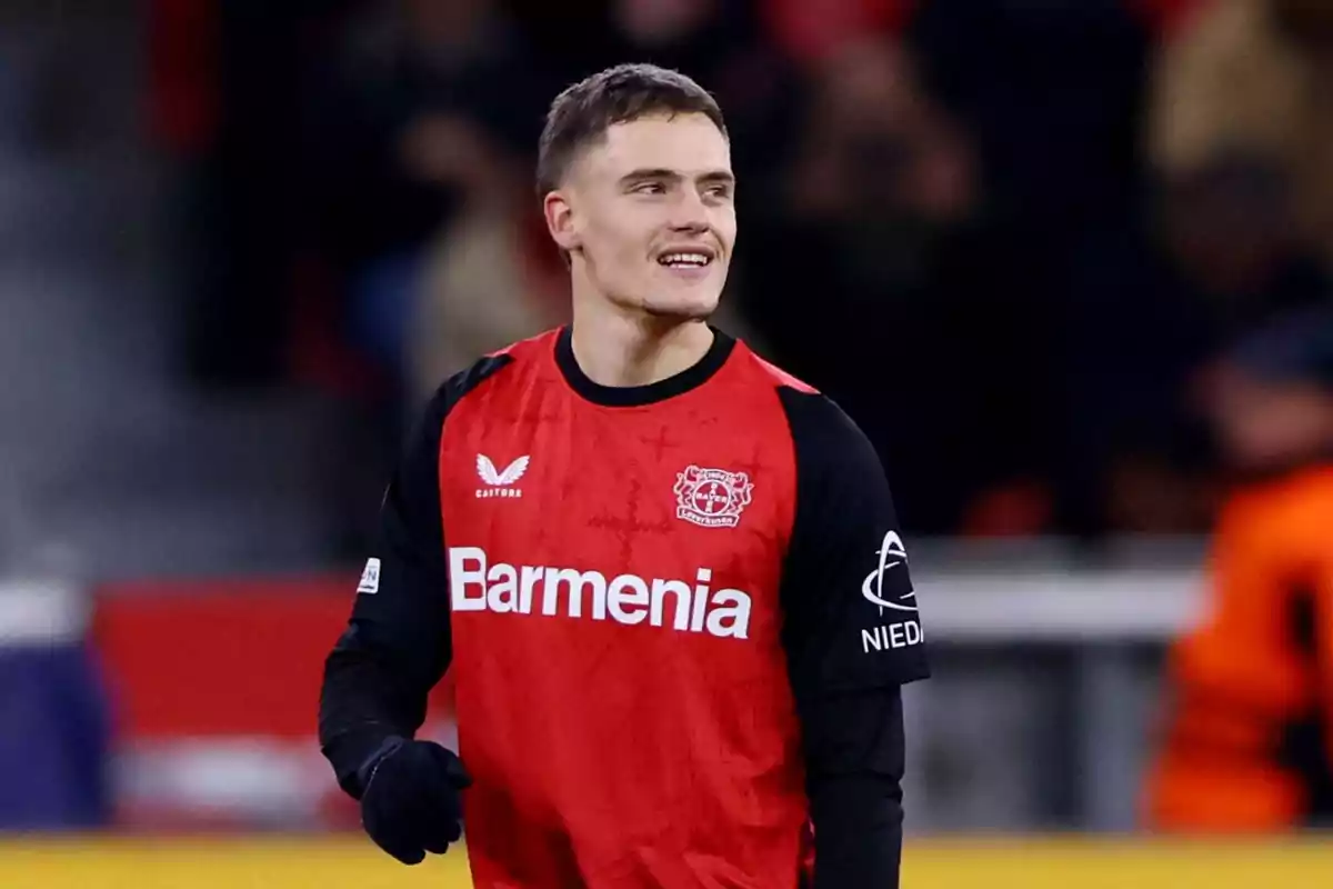 Soccer player in a red and black Bayer Leverkusen uniform smiles during a match Soccer player in a red and black Bayer Leverkusen uniform smiles during a match