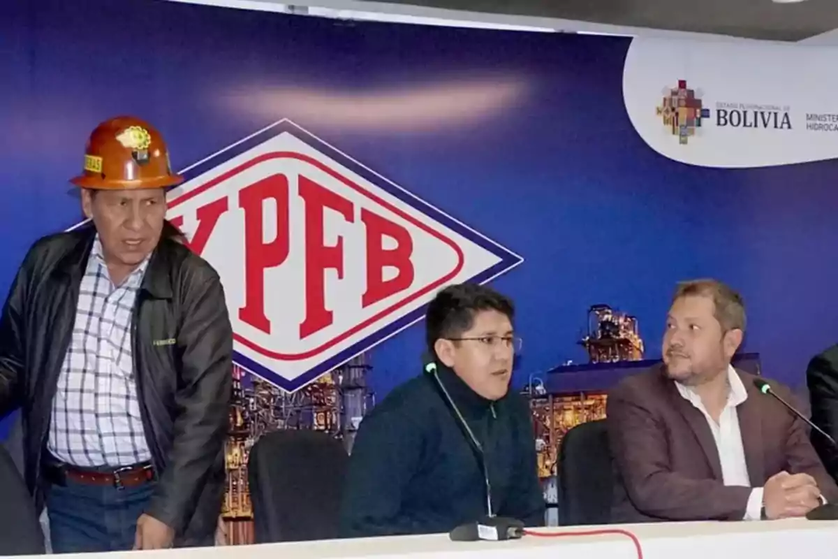Tres personas en una conferencia de prensa frente a un cartel de YPFB y el logo del Ministerio de Hidrocarburos de Bolivia, una de ellas lleva un casco de seguridad. Tres personas en una conferencia de prensa frente a un cartel de YPFB y el logo del Ministerio de Hidrocarburos de Bolivia, una de ellas lleva un casco de seguridad.