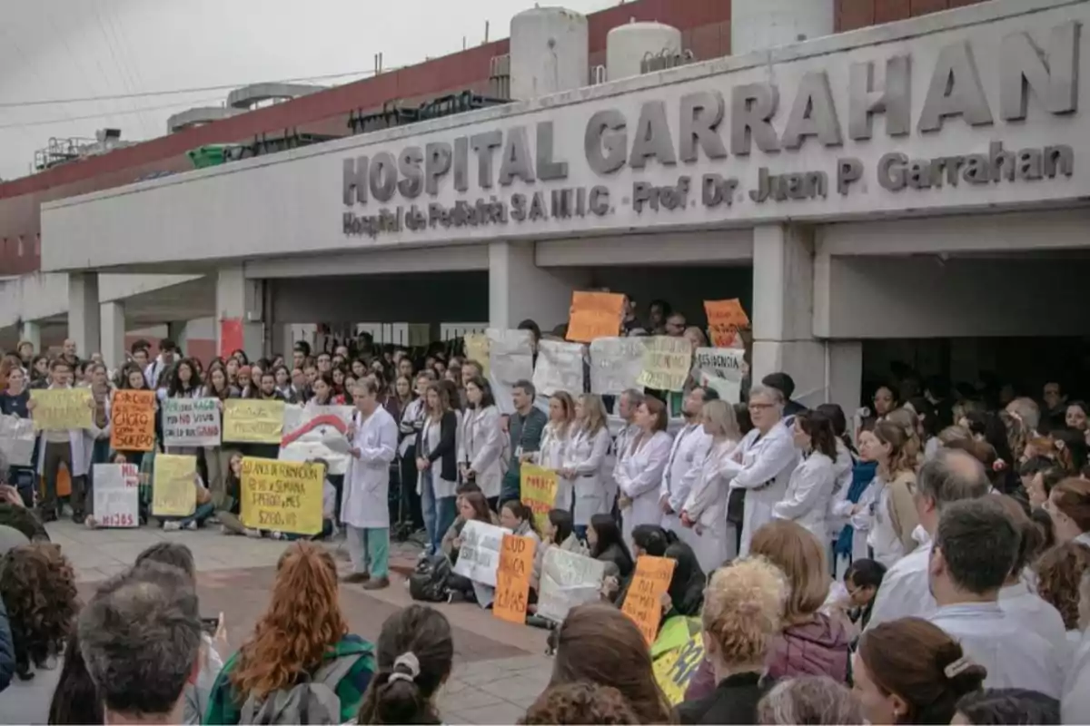 A large group of doctors and healthcare workers are protesting with signs in front of the entrance to Garrahan Hospital.