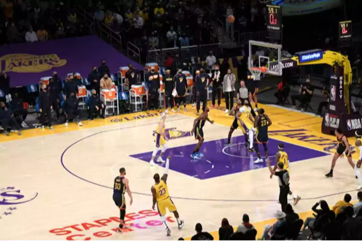 Jugadores de los Lakers y Warriors disputan un partido de baloncesto en el Staples Center con el público observando desde las gradas Jugadores de los Lakers y Warriors disputan un partido de baloncesto en el Staples Center con el público observando desde las gradas