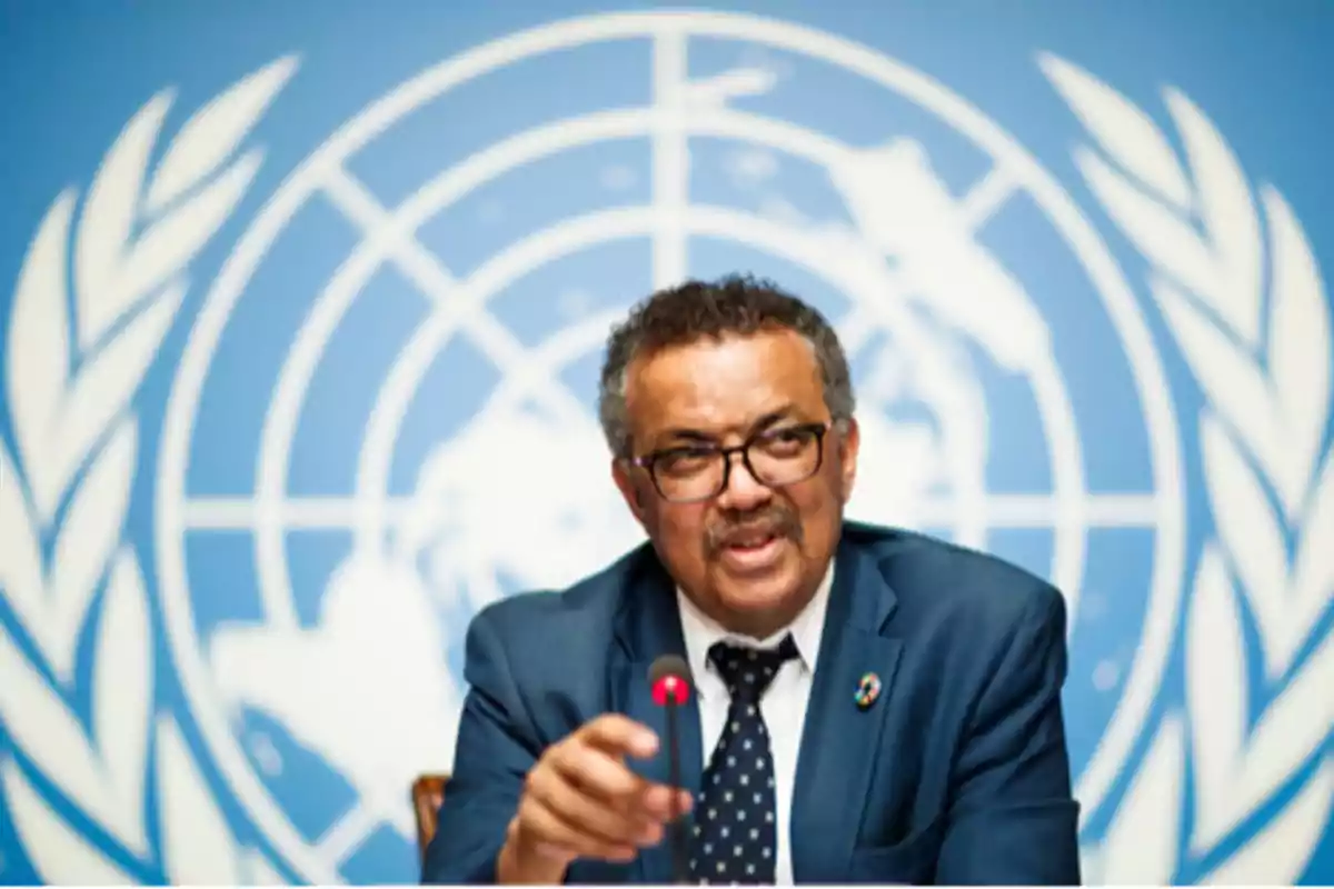 Un hombre con gafas y traje oscuro habla en un micrófono frente a un fondo con el logotipo de la ONU. Un hombre con gafas y traje oscuro habla en un micrófono frente a un fondo con el logotipo de la ONU.