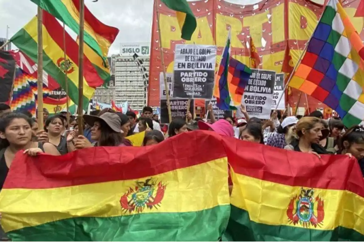 Personas marchando con banderas de Bolivia y pancartas en una manifestación.