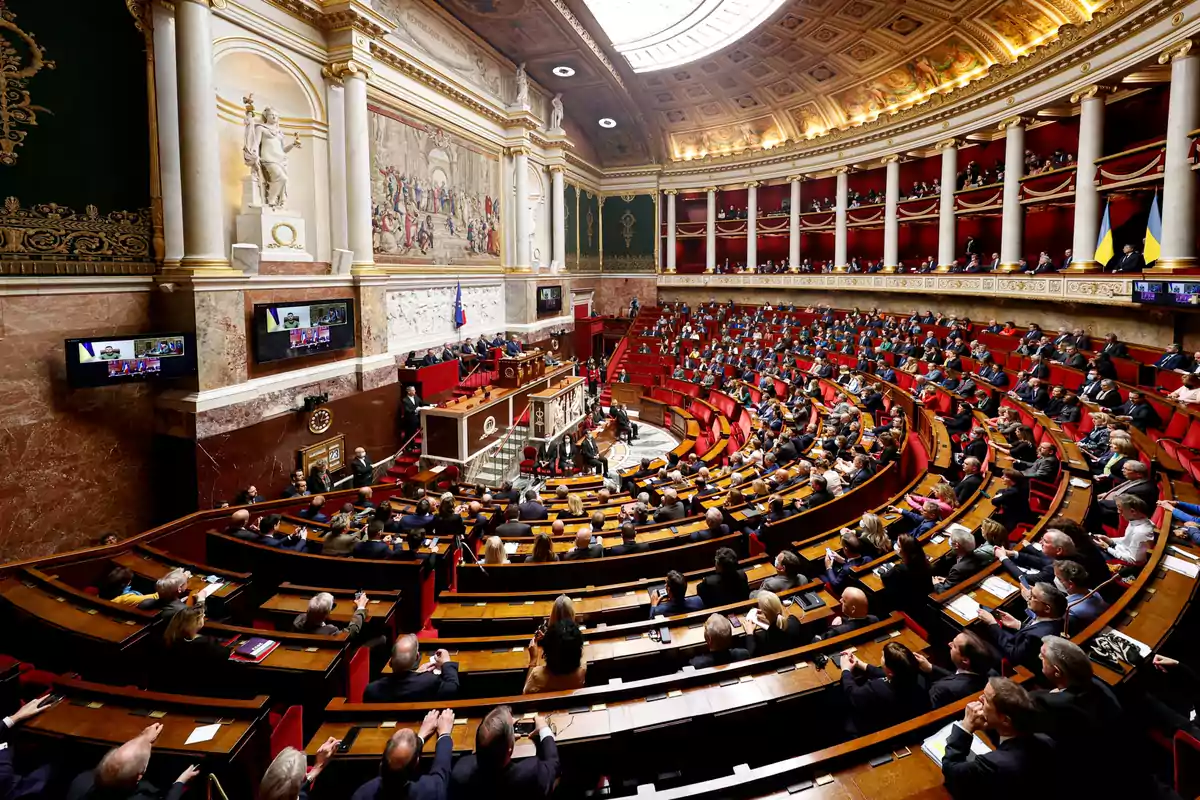 Una asamblea legislativa con numerosos asistentes sentados en un hemiciclo rodeado de columnas y decoraciones clásicas.