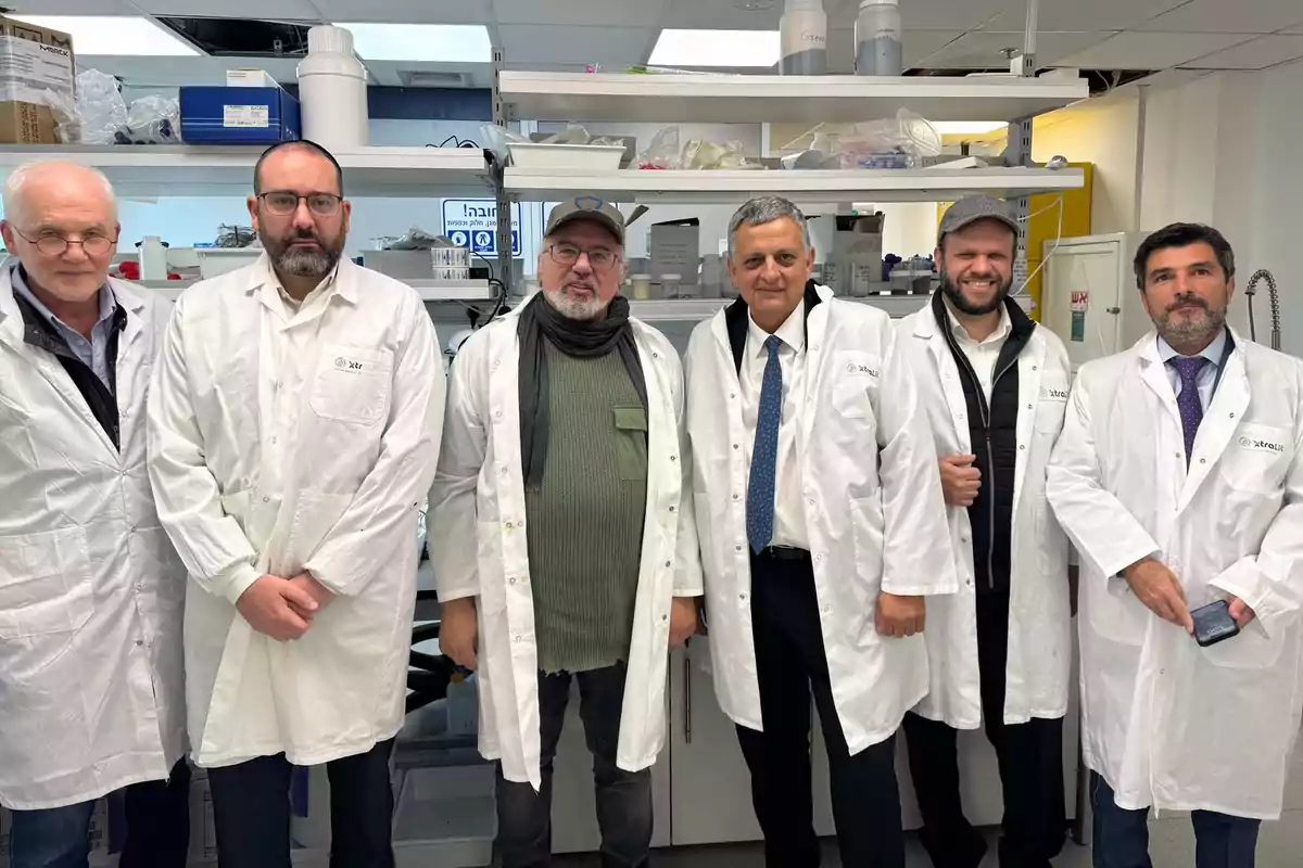 A group of men in lab coats pose in a laboratory setting.
