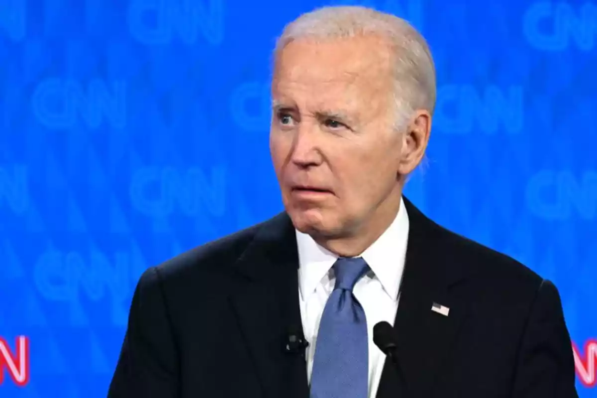 A gray-haired man in a dark suit with a blue tie is in front of a blue background with CNN logos. A gray-haired man in a dark suit with a blue tie is in front of a blue background with CNN logos.