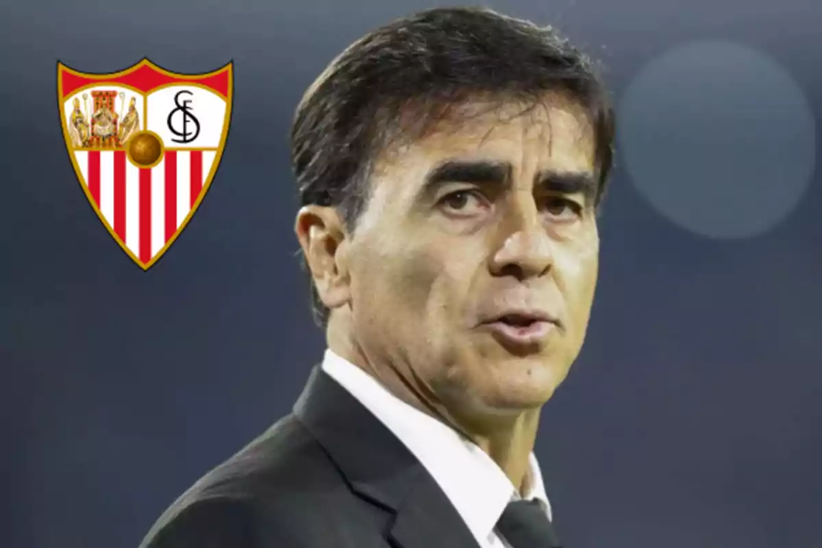 Man in a dark suit and tie, next to the Sevilla FC crest, against a blurred background. Man in a dark suit and tie, next to the Sevilla FC crest, against a blurred background.
