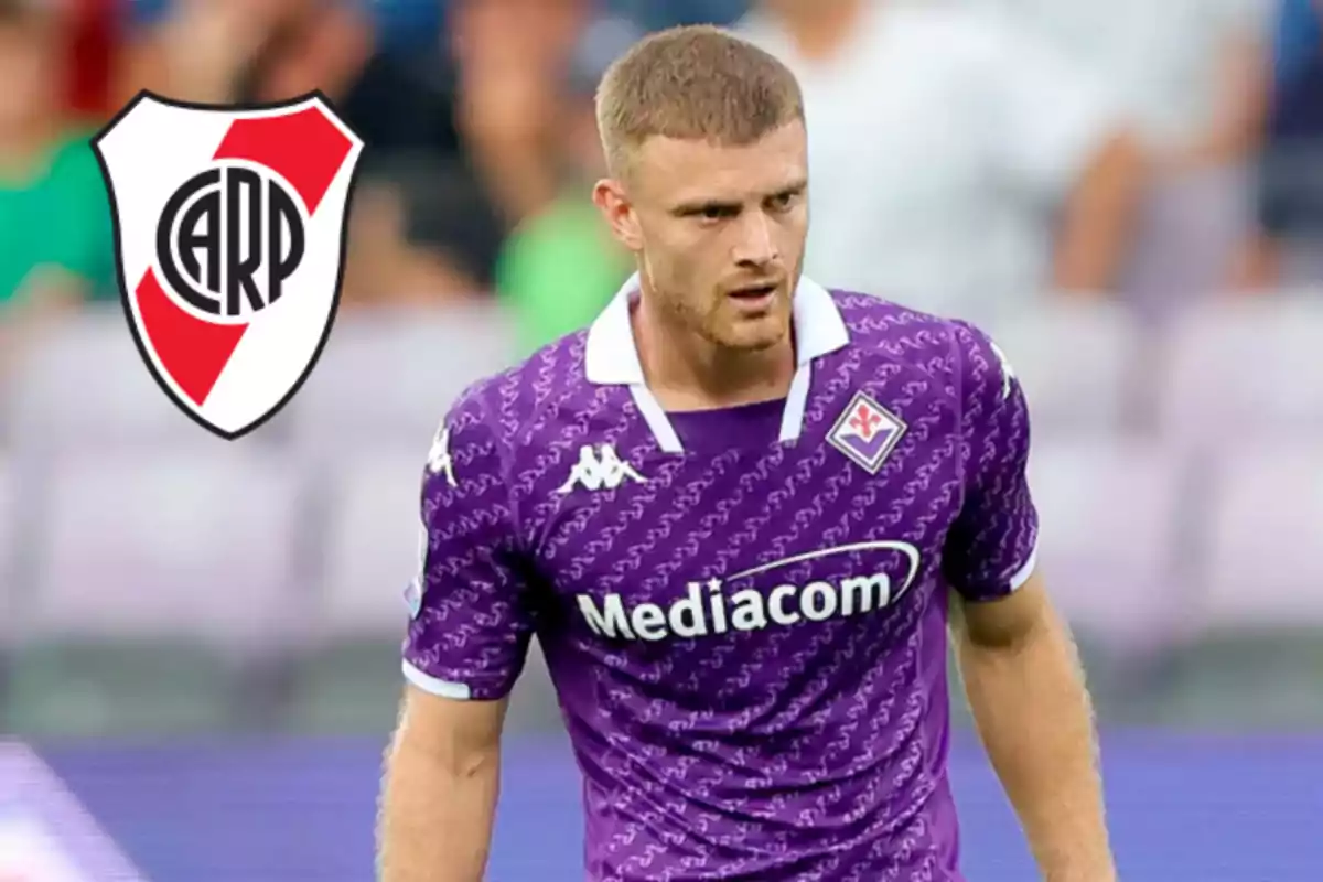 A player wearing a purple Fiorentina jersey with the River Plate crest in the background.