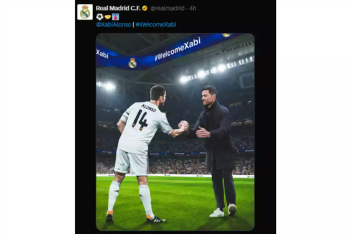 Un jugador de fútbol con el número 14 en su camiseta saluda a un hombre vestido de traje en un estadio iluminado, con un mensaje de bienvenida en la pantalla del estadio. Un jugador de fútbol con el número 14 en su camiseta saluda a un hombre vestido de traje en un estadio iluminado, con un mensaje de bienvenida en la pantalla del estadio.