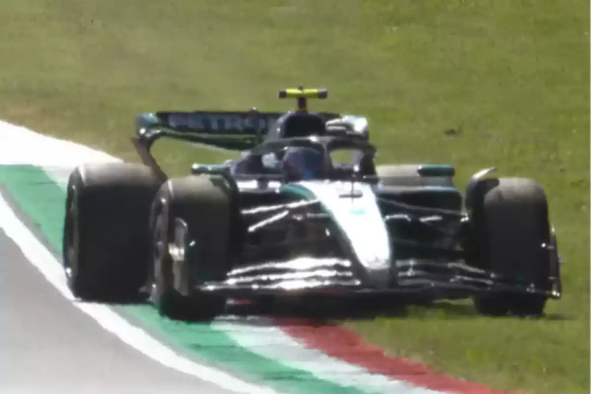 A black and silver Formula 1 car is driving on a racetrack, partially on the grass. A black and silver Formula 1 car is driving on a racetrack, partially on the grass.