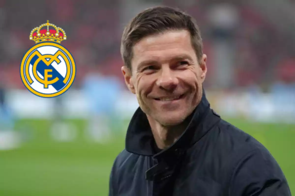 Un hombre sonriendo con el logo del Real Madrid al fondo.