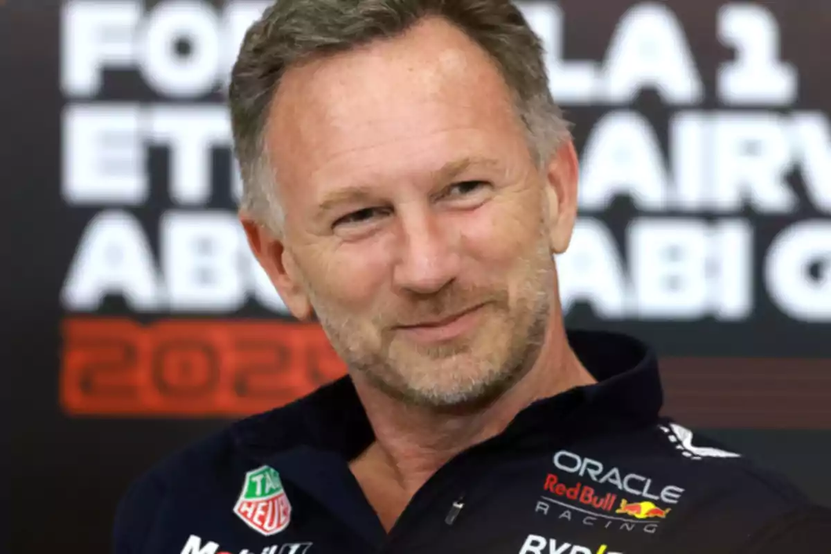 Middle-aged man with a short beard and brown hair, smiling while wearing a Red Bull Racing jacket in front of a background with blurred letters Middle-aged man with a short beard and brown hair, smiling while wearing a Red Bull Racing jacket in front of a background with blurred letters