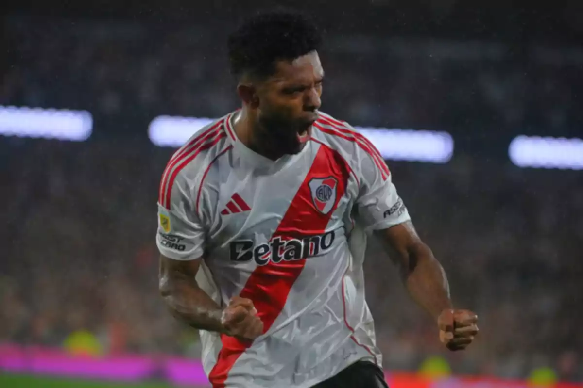 Un jugador de fútbol con uniforme blanco y rojo celebra con entusiasmo en el campo. Un jugador de fútbol con uniforme blanco y rojo celebra con entusiasmo en el campo.