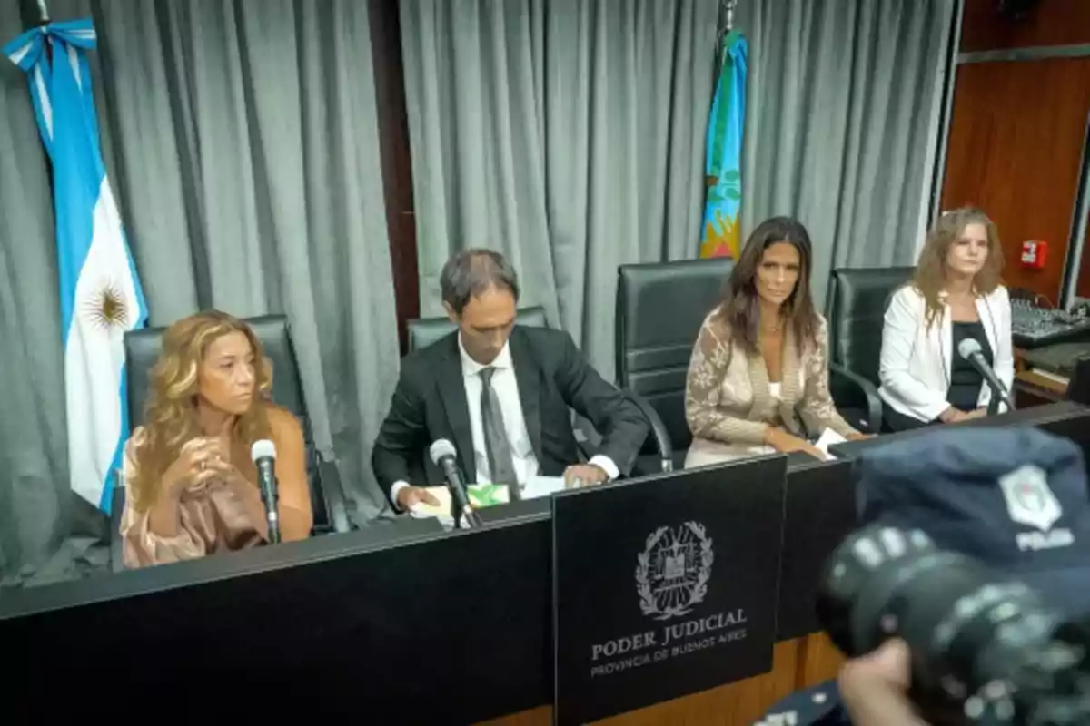 Cuatro personas sentadas en una mesa del Poder Judicial de la Provincia de Buenos Aires con banderas argentinas de fondo y micrófonos frente a ellas Cuatro personas sentadas en una mesa del Poder Judicial de la Provincia de Buenos Aires con banderas argentinas de fondo y micrófonos frente a ellas