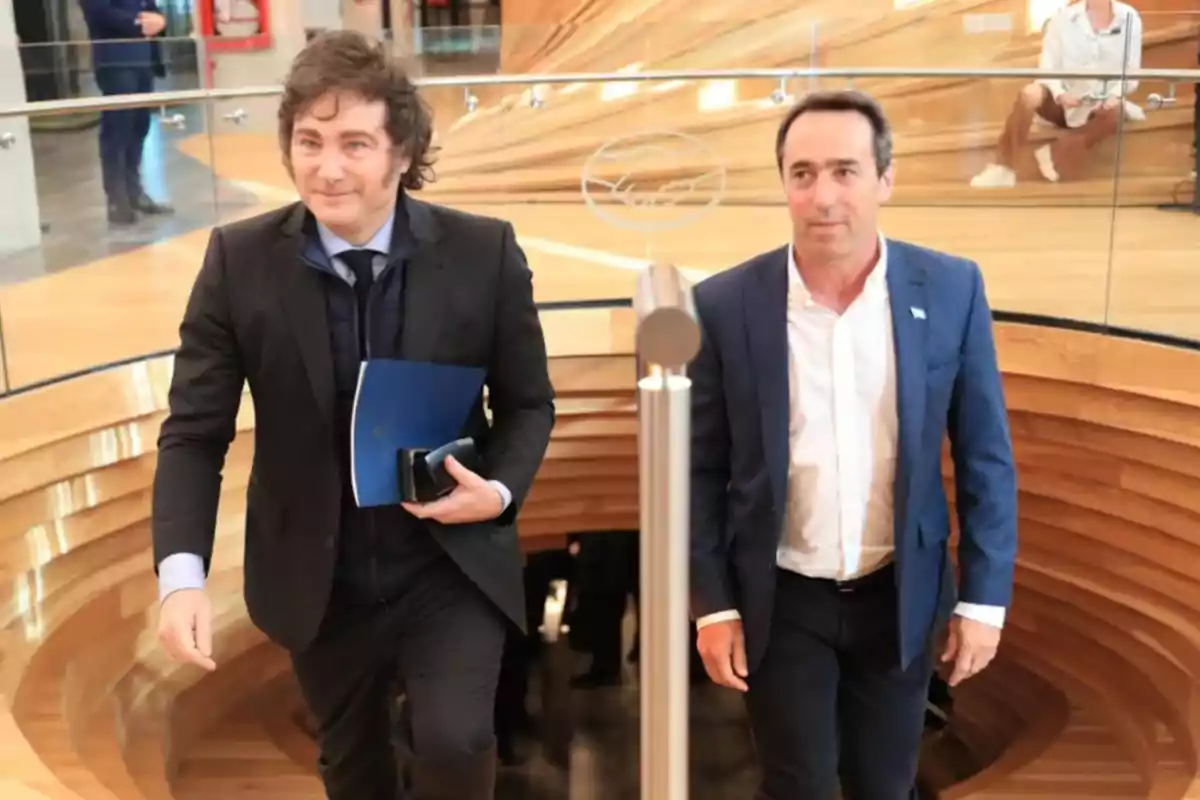 Two men climb a wooden ladder in a modern building, one carries a blue document and the other wears a blue suit. Two men climb a wooden ladder in a modern building, one carries a blue document and the other wears a blue suit.