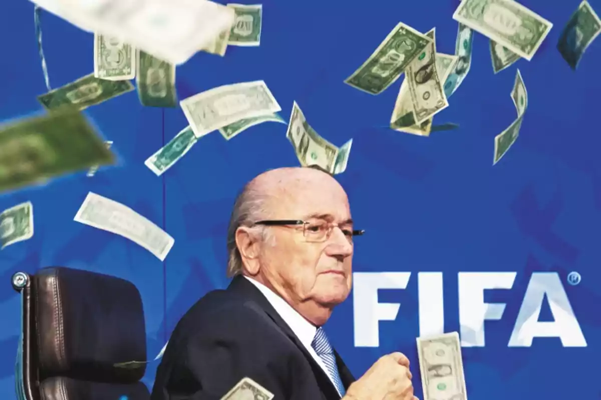 An older man in a dark suit is sitting in front of a blue background with the FIFA logo as dollar bills fall around him. An older man in a dark suit is sitting in front of a blue background with the FIFA logo as dollar bills fall around him.