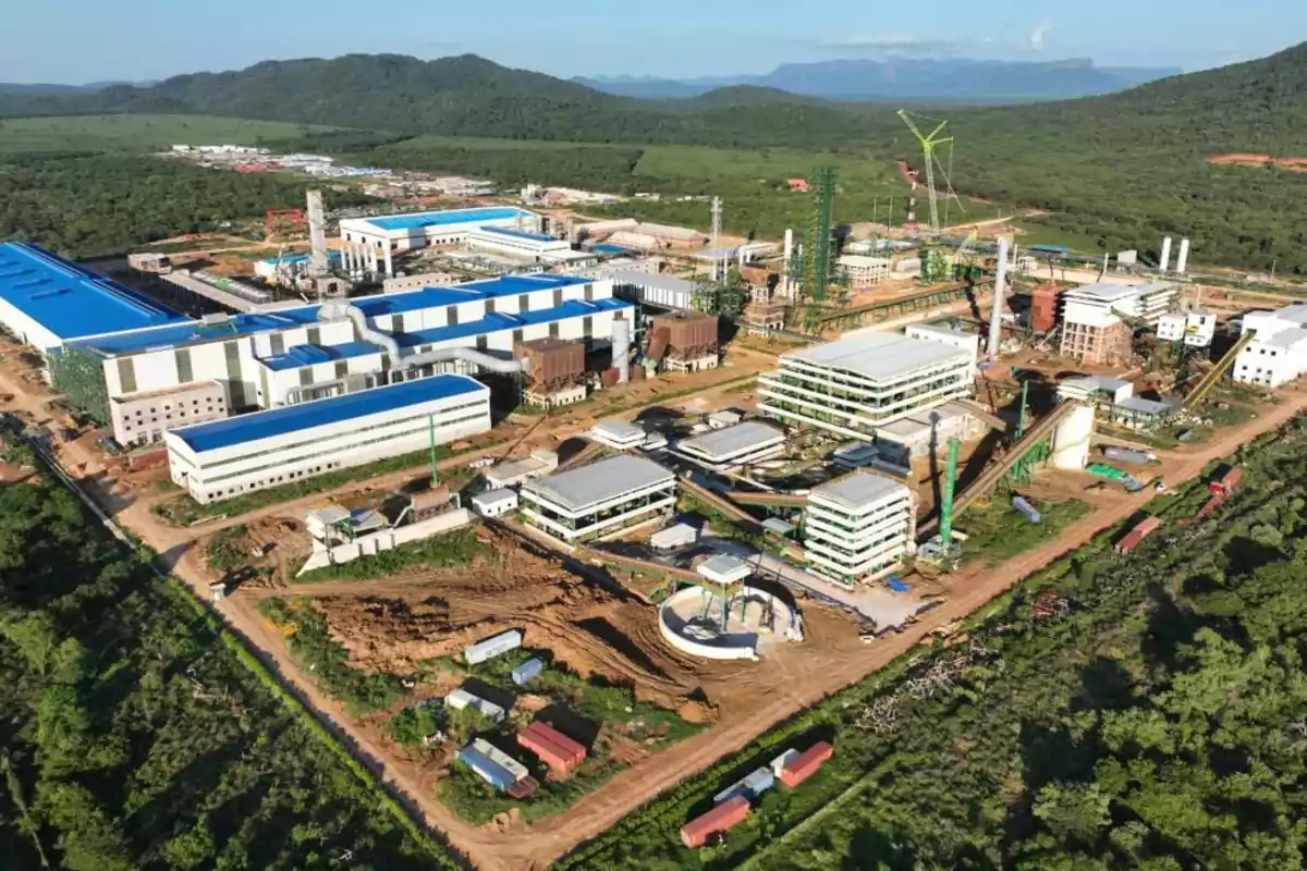 Vista aérea de un complejo industrial rodeado de vegetación y montañas.