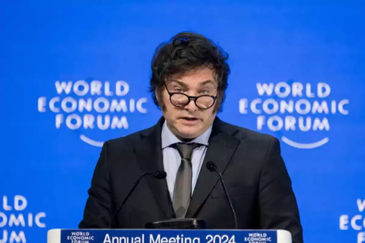 Un hombre con gafas y traje habla en un podio durante el World Economic Forum.