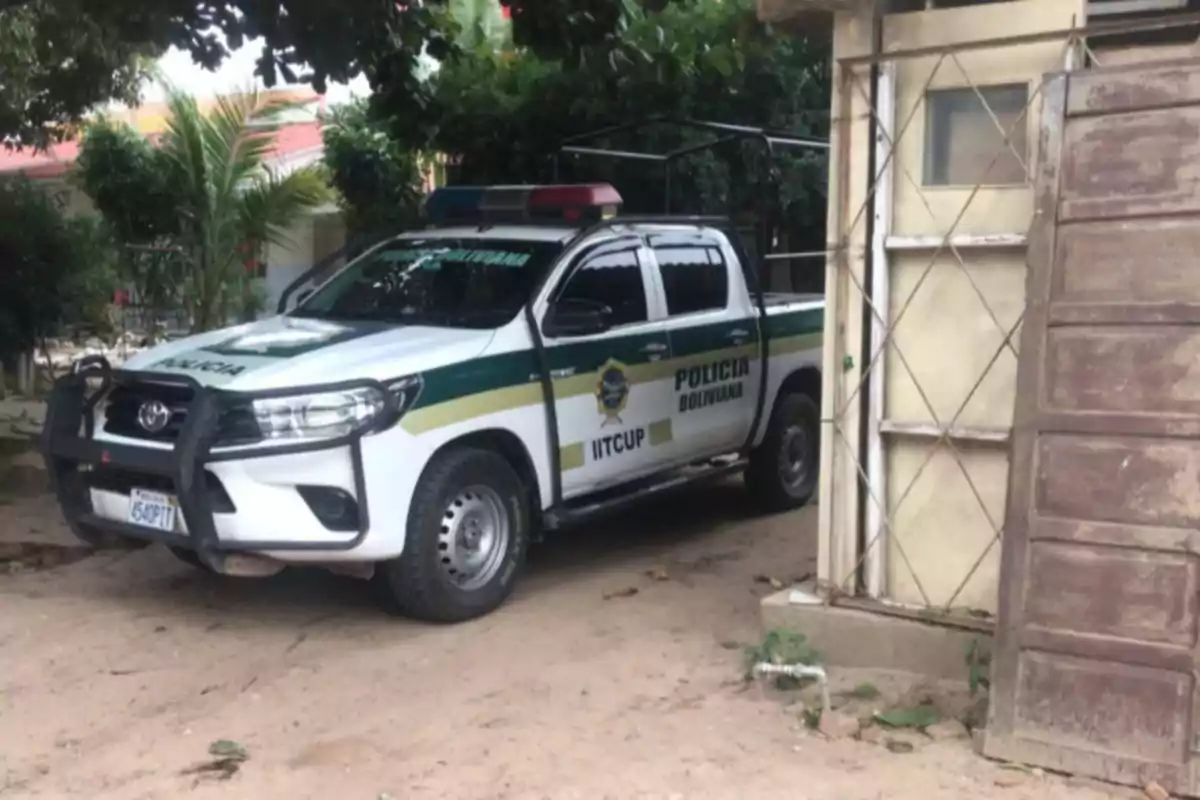 Camioneta de la policía boliviana estacionada junto a una casa rodeada de vegetación