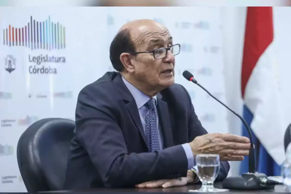Man in a suit and glasses speaking into a microphone during a conference at the Córdoba Legislature Man in a suit and glasses speaking into a microphone during a conference at the Córdoba Legislature