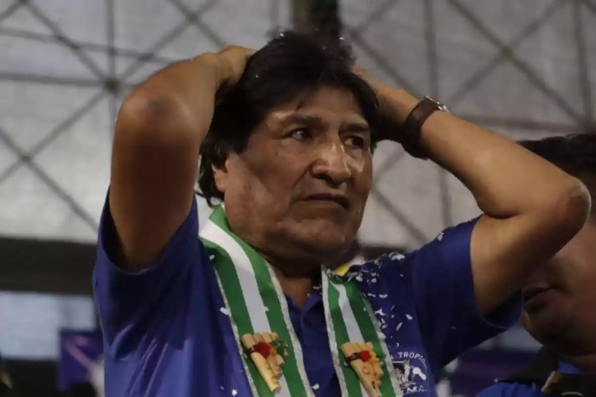 A man in a blue jersey and a green and white band holds his head in an indoor place.