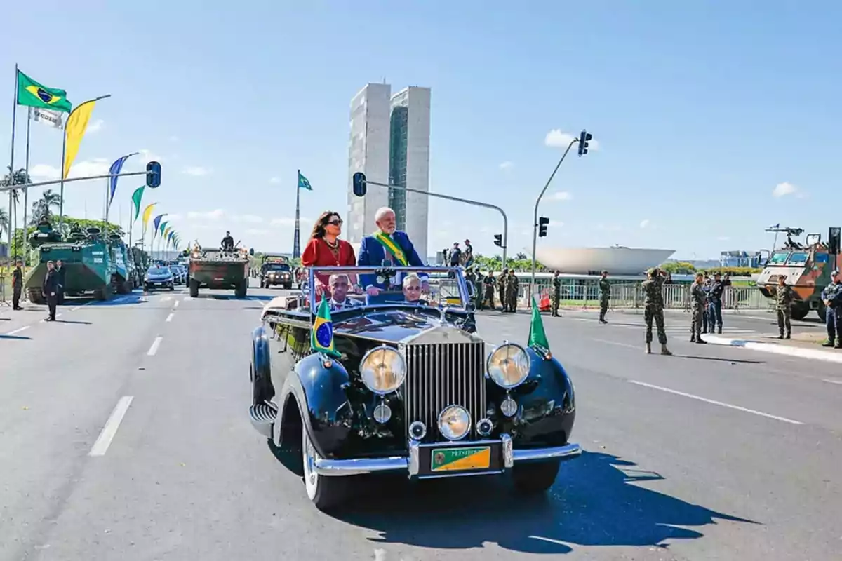 Desfile militar en Brasilia con un automóvil clásico y personas destacadas, con el Congreso Nacional de Brasil al fondo.