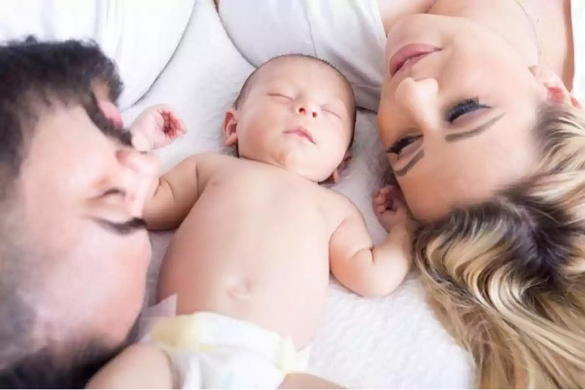 A couple lying in bed watching their sleeping baby. A couple lying in bed watching their sleeping baby.