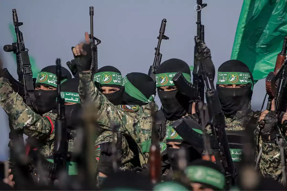 Grupo de hombres armados con uniformes de camuflaje y pañuelos verdes en la cabeza sosteniendo rifles