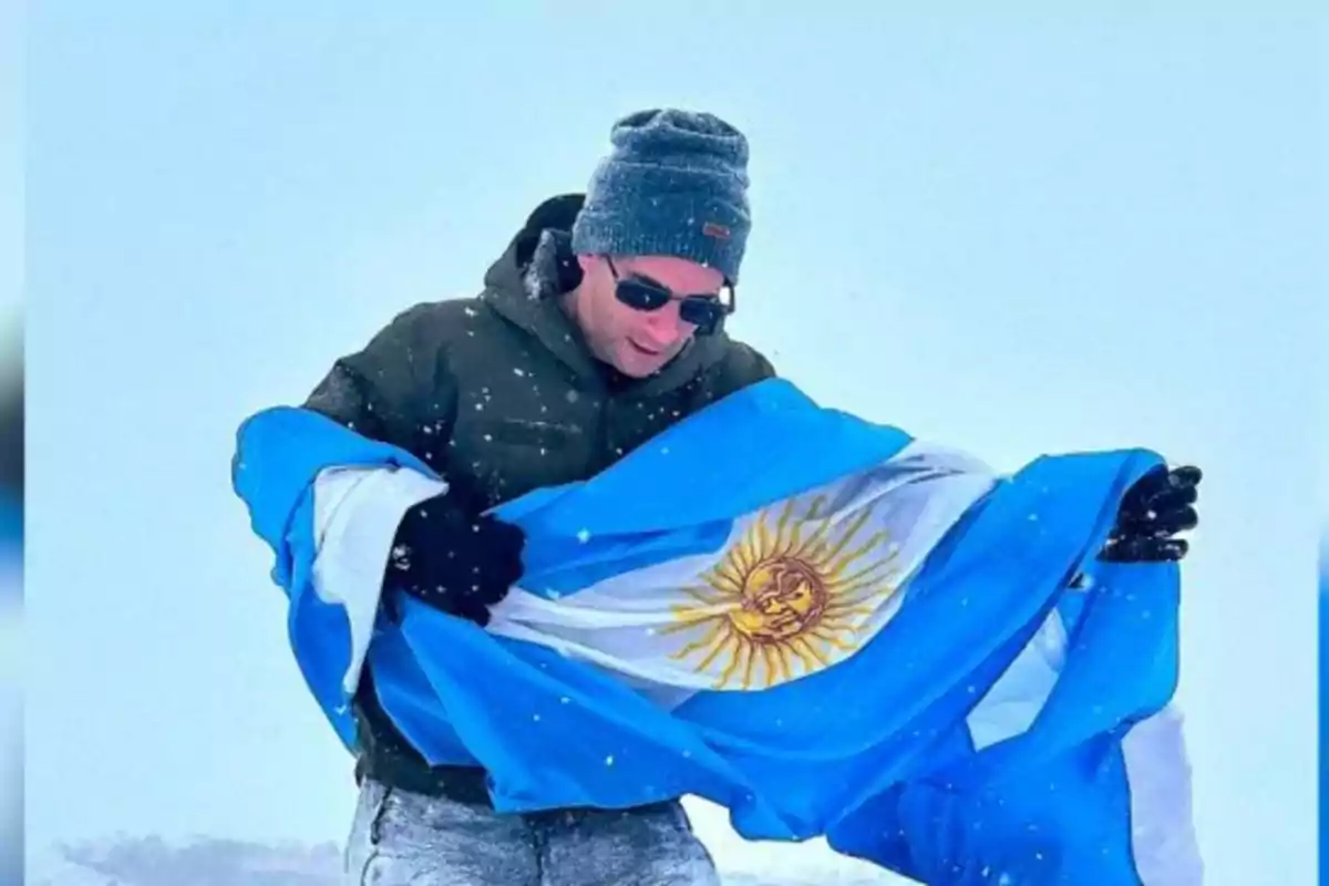 Persona sosteniendo una bandera argentina en un entorno nevado.