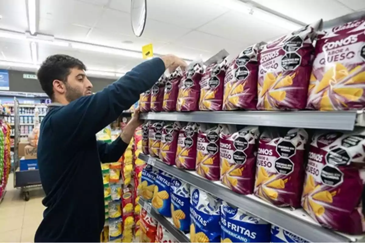 Un hombre organiza bolsas de snacks en un estante de supermercado. Un hombre organiza bolsas de snacks en un estante de supermercado.